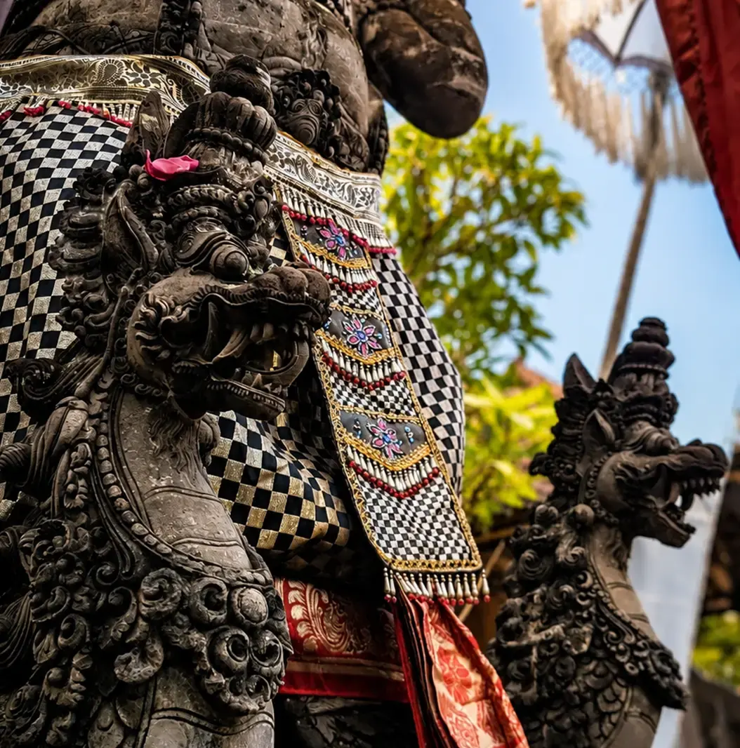 Carved stone guardians dressed in checked cloth for a ceremony